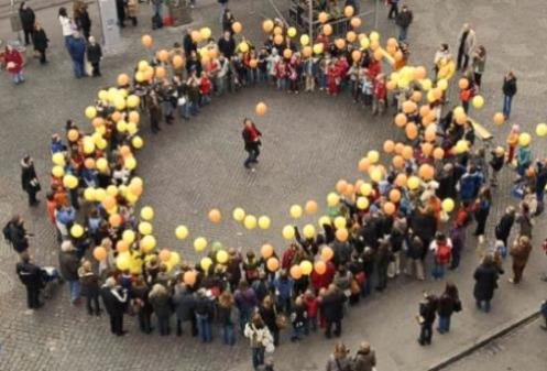 Ein Kreis von Menschen mit gelben Ballonen auf dem Marktplatz 